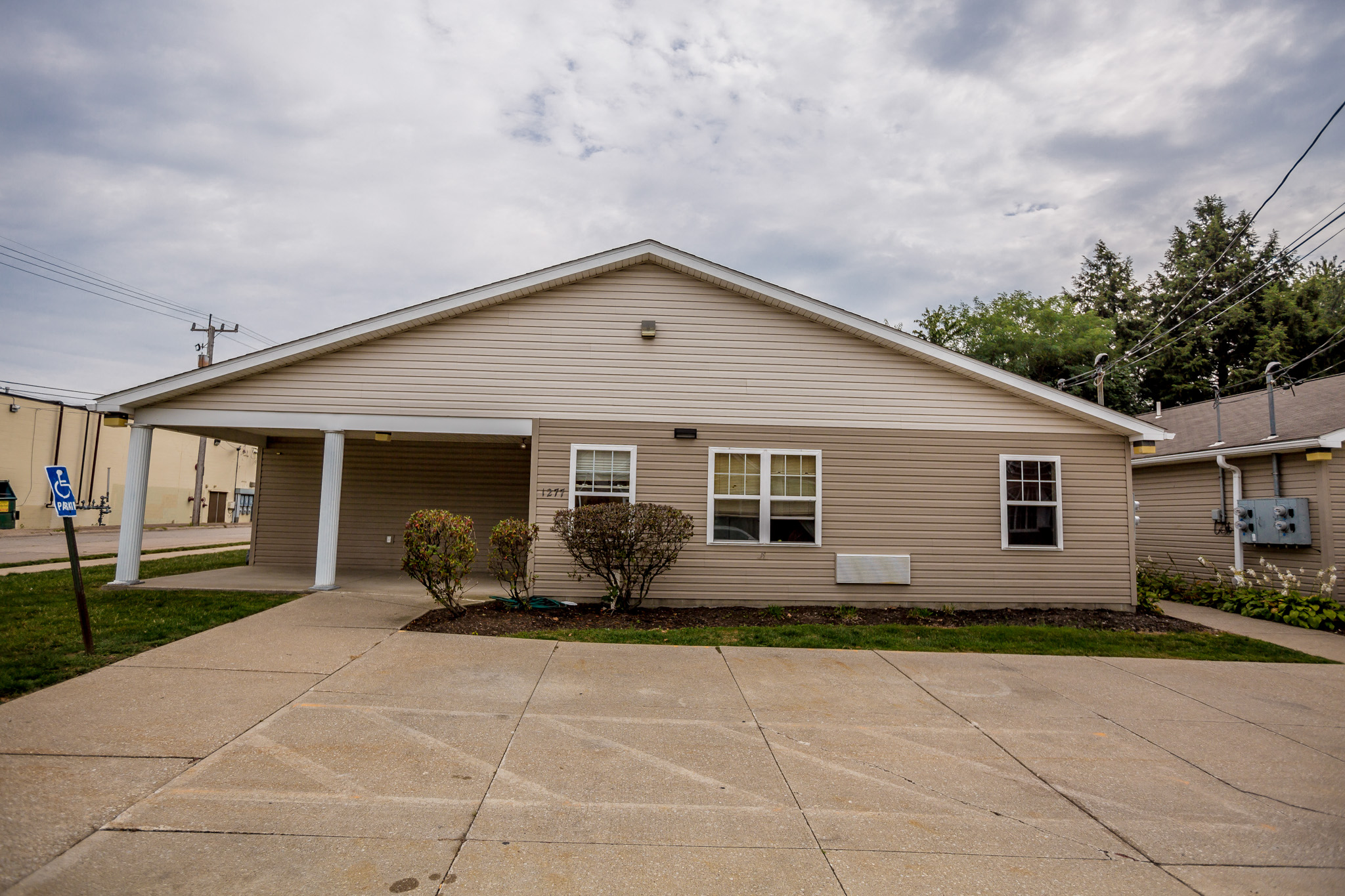 a small tan house with a driveway in front of it